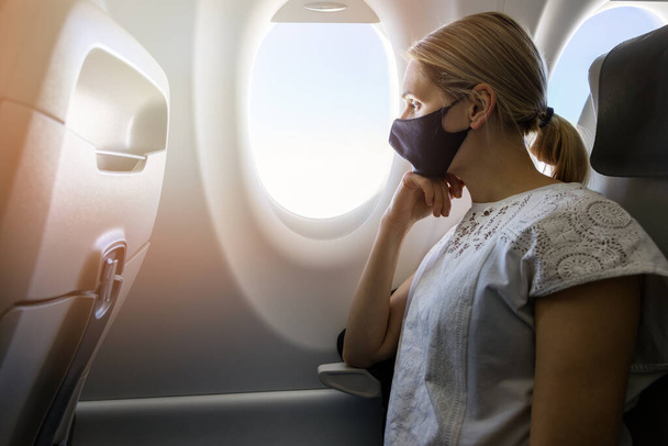 Frau mit Mundschutz im Flugzeug. Neuer Normalreiseverkehr - Foto, Bild
