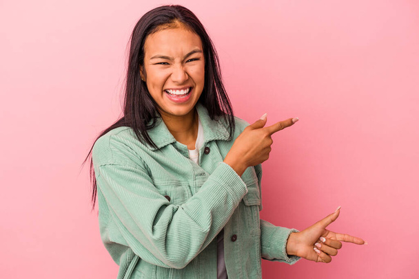Junge lateinische Frau isoliert auf rosa Hintergrund aufgeregt zeigt mit Zeigefingern weg. - Foto, Bild