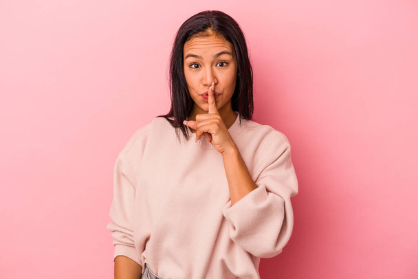 Junge lateinamerikanische Frau isoliert auf rosa Hintergrund hält ein Geheimnis oder bittet um Schweigen. - Foto, Bild