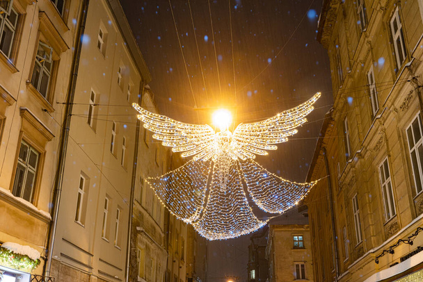 Décoration illuminée de Noël d'ange accroché sur la rue Lviv la nuit - Photo, image