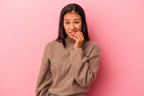 Jonge latijnse vrouw geïsoleerd op roze achtergrond bijten nagels, nerveus en zeer angstig. - Foto, afbeelding