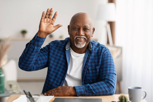 Vanhempi musta liikemies heiluttaa käsi videopuhelu kautta kannettava tietokone sisätiloissa - Valokuva, kuva