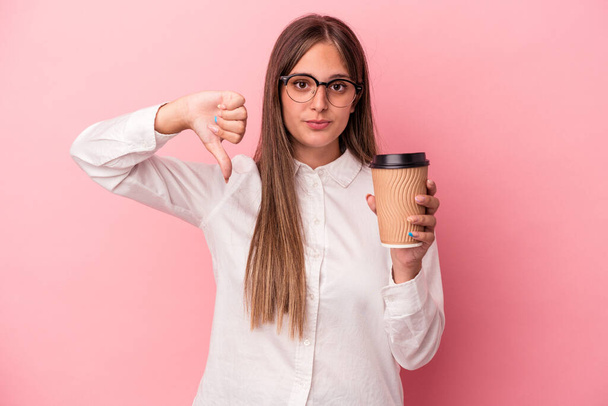 Young business caucasian woman holding a take away isolated on pink background showing a dislike gesture, thumbs down. Disagreement concept. - Foto, Imagem