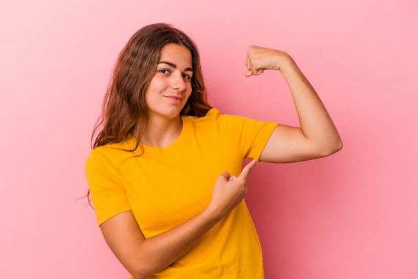 Young caucasian woman isolated on pink background  showing strength gesture with arms, symbol of feminine power - Photo, image