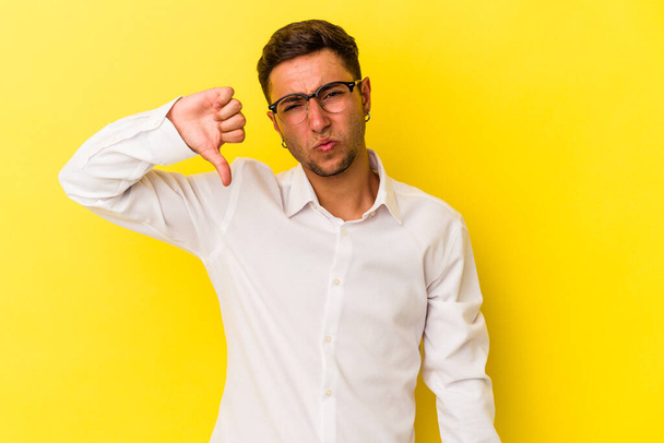 Young caucasian man with tattoos isolated on yellow background  showing thumb down and expressing dislike. - Photo, Image