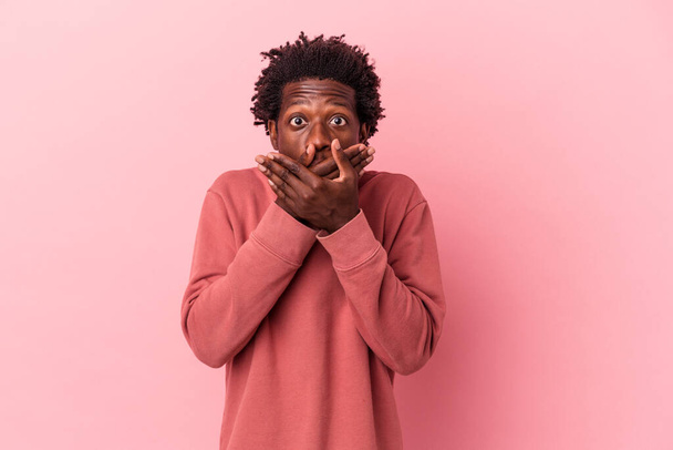 Fiatal afro-amerikai férfi elszigetelt rózsaszín háttér sokkolt fedő száj kezével. - Fotó, kép