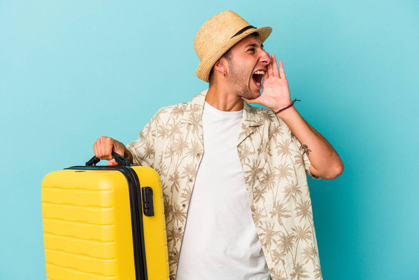 Young caucasian man going to travel isolated on blue background  shouting and holding palm near opened mouth. - Photo, Image