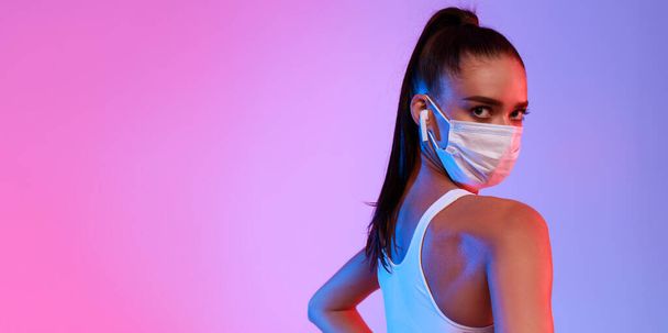 Portrait Of Fit Woman Wearing Face Mask Over Neon Background - 写真・画像