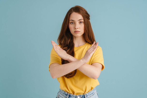 Young ginger white woman showing stop gesture and looking at camera isolated over blue background - Photo, Image