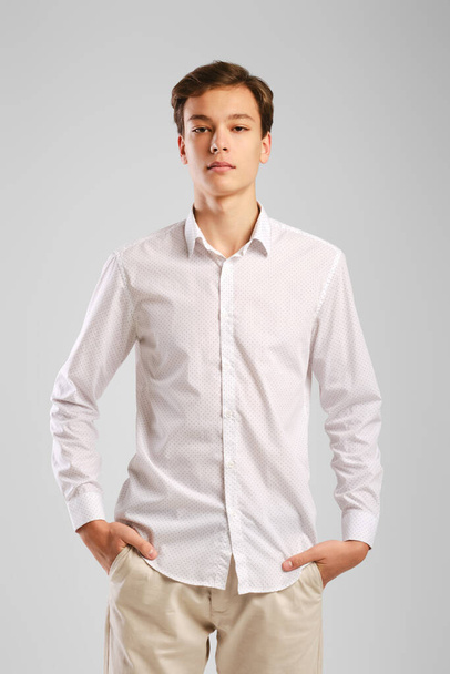 Calm young man in white shirt and trousers with hands in the pockets - Fotografie, Obrázek