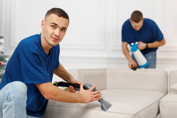 Πορτρέτο των δύο εργαζομένων καθαρισμού ευτυχώς καθαρισμό καναπέ - Φωτογραφία, εικόνα
