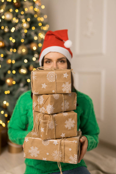 La joven sonriente sostiene regalos marrones cerca del árbol festivo de Navidad - Foto, imagen