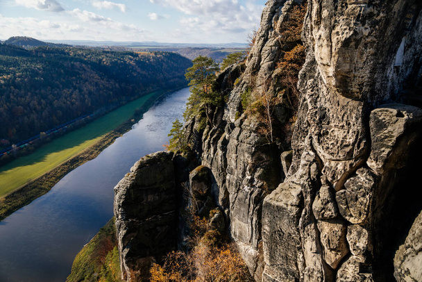 Saxon Switzerland National Park, Germany, 6 November 2021: Basteiaussicht or Bastei Rock Formations in Elbe River Valley, Sandstone Mountains Path, autumn forest landscape at sunny day, rocky valley  - Photo, image
