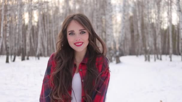 Bájos nő hosszú hajjal sétál a havas erdőben - Felvétel, videó