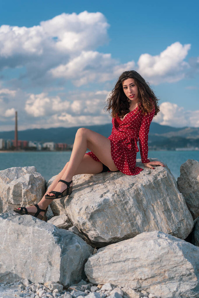 A vertical shot of a Caucasian sexy woman with a red dress in a seashore - Foto, Imagem