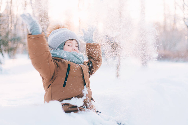 The boy throws snow in winter lifestyle . Winter walks. An article about children's winter leisure. Entertainments - 写真・画像
