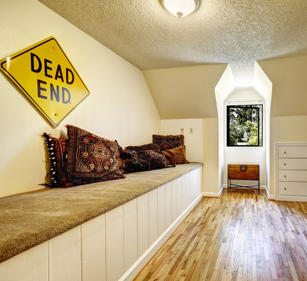 Лавка з килимовим покриттям і коричневими подушками у порожній кімнаті
 - Фото, зображення