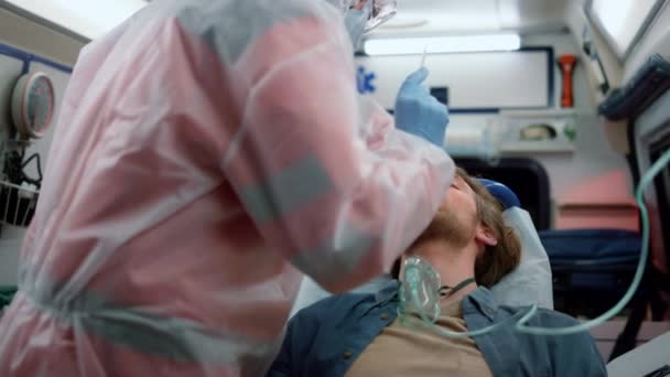 Sanitäter machen Nasenabstrich-Test auf Coronavirus des Mannes im Notarztwagen - Filmmaterial, Video