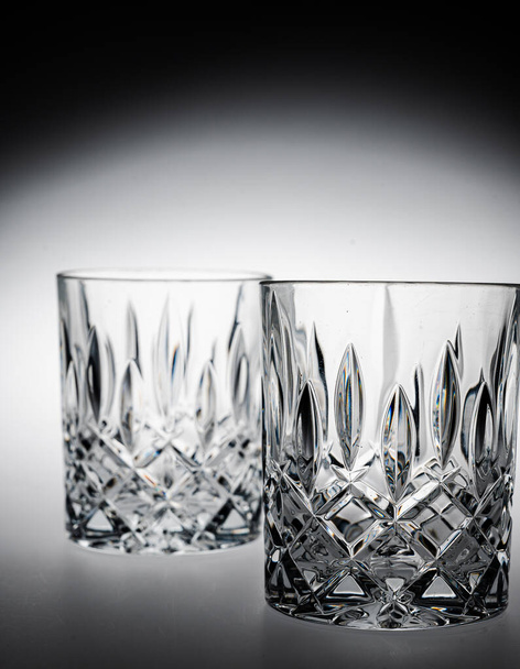 A vertical closeup of two whiskey glasses. - 写真・画像