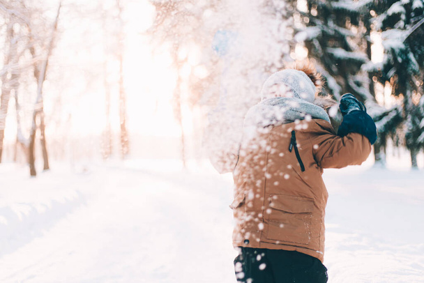 Der Junge wirft mit einer Schaufel Schnee. Winterwanderungen. Ein Artikel über die Winterfreizeit für Kinder. Unterhaltung - Foto, Bild