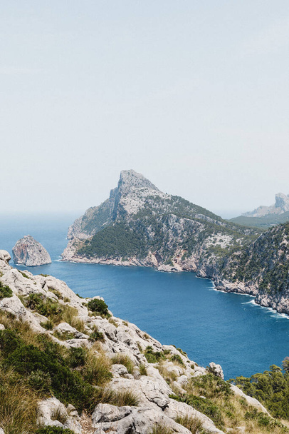 Eine vertikale Aufnahme der Klippen und des blauen Meeres. Mirador Es Colomer, Spanien. - Foto, Bild