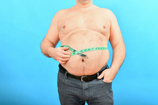 Tlustý a břichatý muž s velkým břichem měří jeho pas centimetrem. - Fotografie, Obrázek