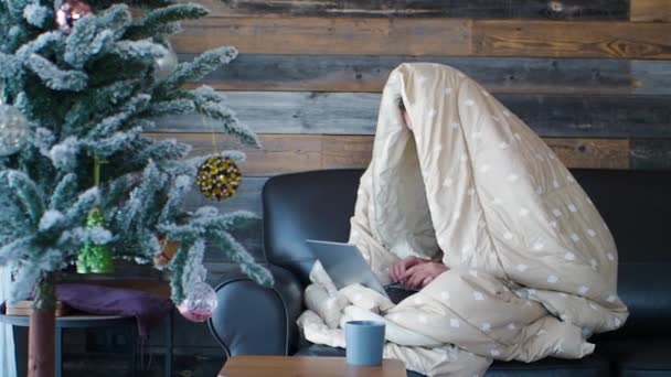 Il lavoro da casa - la donna assonnata sotto le coperture lavora davanti a un monitor di computer portatile e beve il caffè del mattino. - Filmati, video