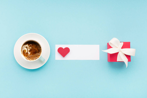 Sevgililer Günü kartı. Kırmızı hediye kutusu, kalp ve bir fincan kahve pastel mavi arka planda. Sevgililer Günü konsepti. Düz konum, üst görünüm, kopyalama alanı. Metin Sevgilim Ol. - Fotoğraf, Görsel
