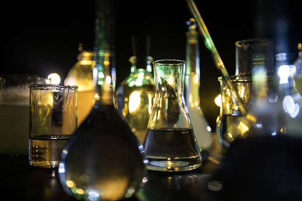 Pharmacy and chemistry theme. Test glass flask with solution in research laboratory. Science and medical background. Laboratory test tubes on dark toned background , science research equipment concept - 写真・画像