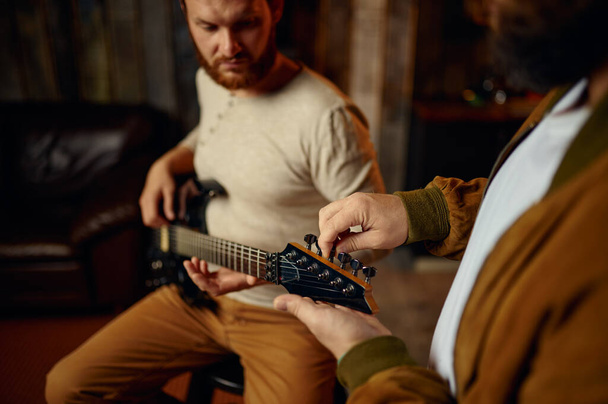 Muzikant die mannelijke student gitaar leert spelen - Foto, afbeelding