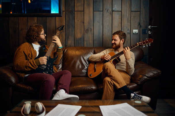 Чоловіки друзі грають на гітарі вдома разом
 - Фото, зображення