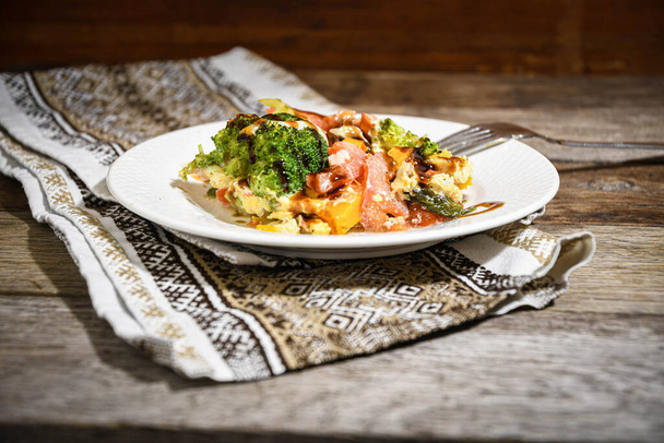 Piatto, salmone con verdure su un piatto bianco su un tovagliolo di cucina su un tavolo da pranzo di legno. Cucina casalinga. - Foto, immagini