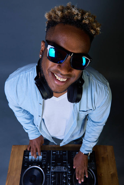 Happy African-American DJ with an Afro hairstyle plays music with sunglasses. - Fotó, kép