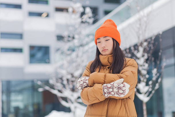 Asian woman on the street frozen in the cold, on a winter snowy day, waiting - 写真・画像