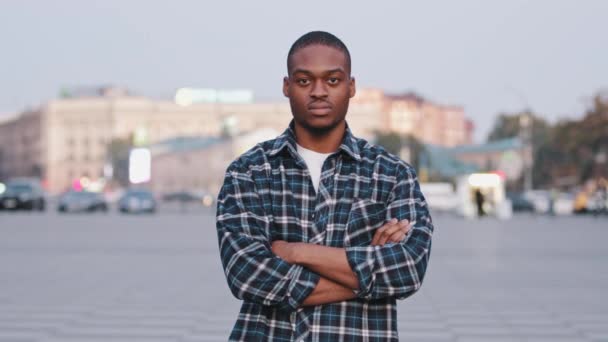 Draußen Porträt männlich afrikanisch-amerikanisch junge ernsthafte Kerl multirassischen Geschäftsmann zuversichtlich Modell Student in lässigem Hemd steht in der Stadt mit gekreuzten Armen posiert aggressiv leistungsstarke Hände kreuzen - Filmmaterial, Video