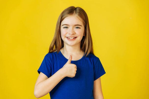cute little girl gesturing thumbs up and looking at camera smiling to camera, - Φωτογραφία, εικόνα
