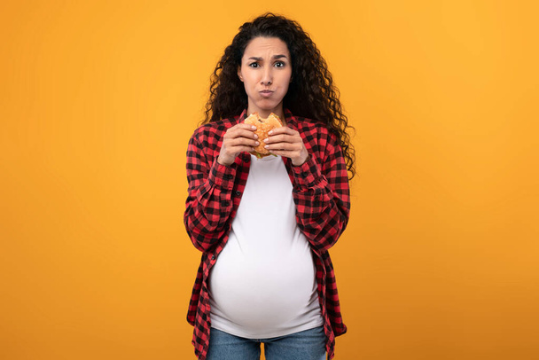 Stüdyoda Burger yiyen hamile kadın. - Fotoğraf, Görsel