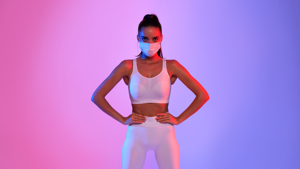 Sporty Young Lady Wearing Face Mask Standing On Neon Background - Foto, imagen
