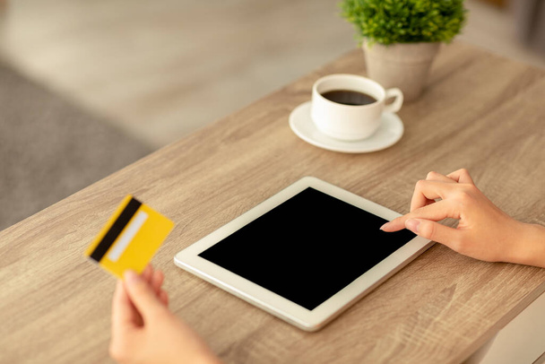 Εύκολες πληρωμές, έννοια του ηλεκτρονικού εμπορίου. Millennial γυναίκα χρησιμοποιώντας tablet με λευκή οθόνη και πιστωτική κάρτα, mockup για το σχεδιασμό - Φωτογραφία, εικόνα