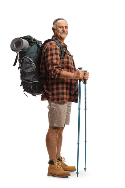 Full length shot of a smiling mature man with a backpack and hiking poles isolated on white background - Photo, Image