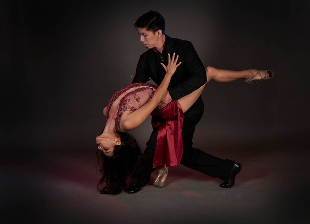 tango ballroom tango ζευγάρι Λατίνων γυναικών και ασιατών ανδρών, στούντιο πυροβόλησε μαύρο φόντο - Φωτογραφία, εικόνα