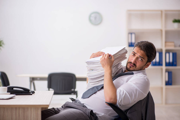 Young male employee and too much work in the office - 写真・画像