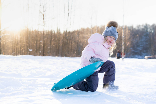 menina cavalga para baixo o slide no gelo, criança alegre, emoções de diversão de inverno - Foto, Imagem