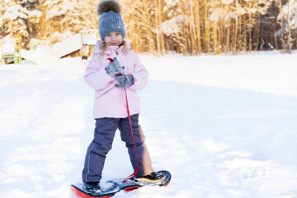 μικρό χαριτωμένο κορίτσι μαθαίνουν να οδηγούν μια παιδική snowboard, χειμερινά σπορ για το παιδί, την ασφάλεια των ενεργών αθλητικών - Φωτογραφία, εικόνα