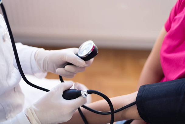 Vrouwelijke geneeskunde arts meten van de bloeddruk aan patiënt - Foto, afbeelding