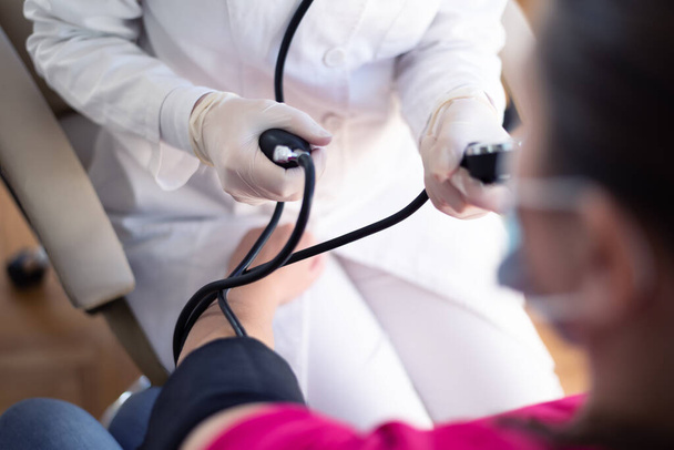 Лікар жіночої медицини вимірює кров'яний тиск для пацієнта
 - Фото, зображення
