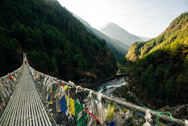 Pont suspendu avec drapeaux de prière bouddhistes sur le circuit de l'Annapurna trek au Népal. Photo de haute qualité - Photo, image
