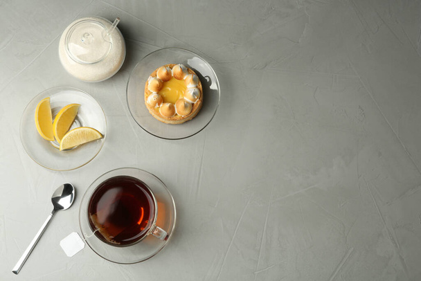 Flat lay composition with tea bag in ceramic cup of hot water and dessert on grey table. Space for text - Foto, immagini