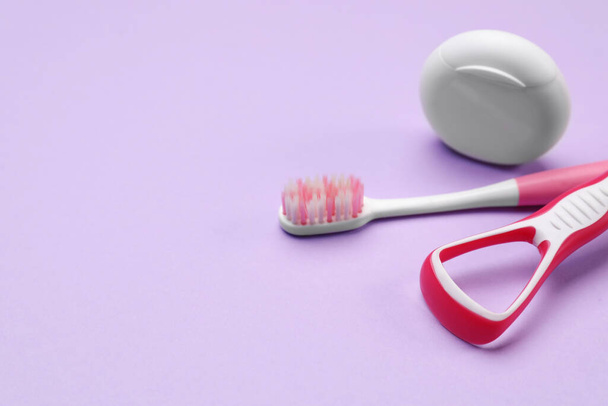 Red tongue cleaner, toothbrush and dental floss on violet background, closeup. Space for text - Photo, Image