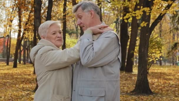 Mutlu yaşlı evli çift sonbahar parkında dans ediyor. Romantik dansın keyfini çıkarın. Yaşlı orta yaşlı büyükanne ve büyükbabayı sevin. - Video, Çekim